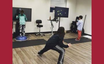 children exercising in therapy room with two tv screens