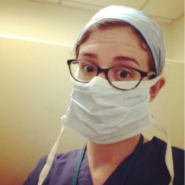 female student wearing glasses, surgical mask, and scrubs