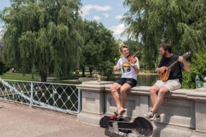 Young musicians play for tips sitting on bridge in Boston Public Gardens