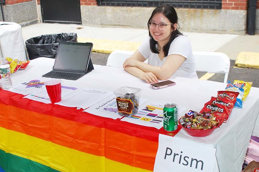 female student sitting at table with pride flag
