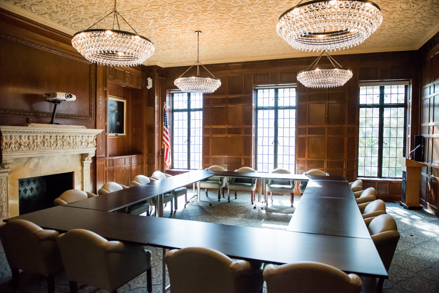 empty formal meeting space with large chandeliers and original paneling on walls